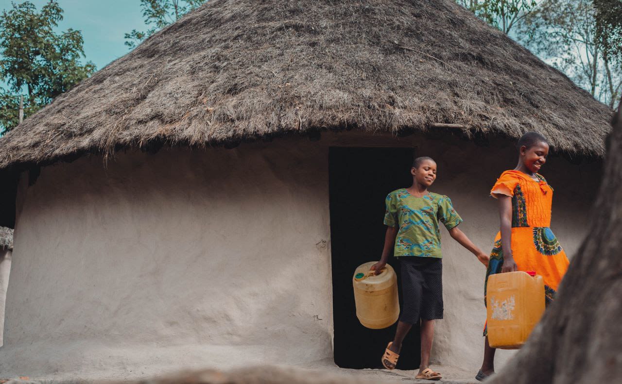 In South Sudan, two young women leave their home to fetch water at their local water distribution point.