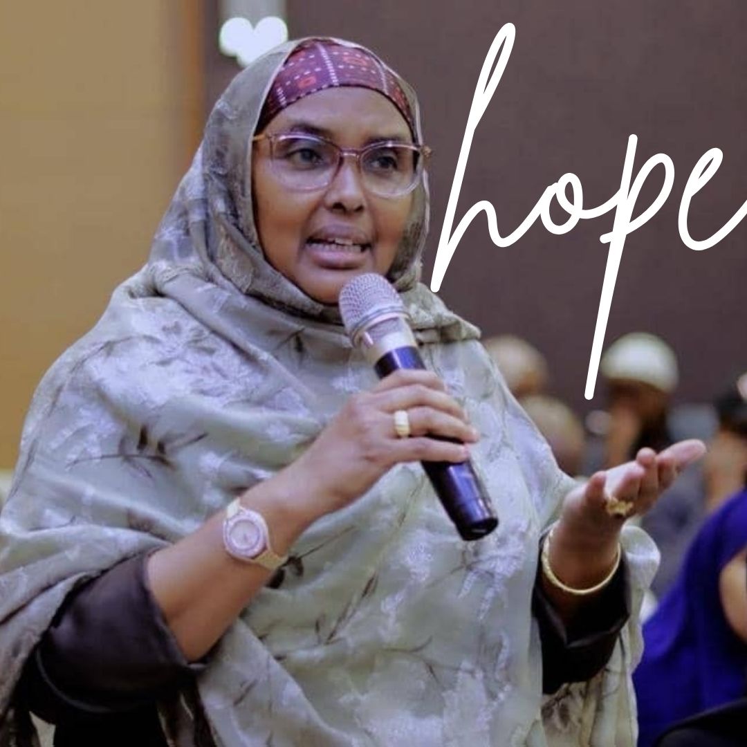  A woman in a headscarf speaks into a microphone with the word "hope" written across the image.