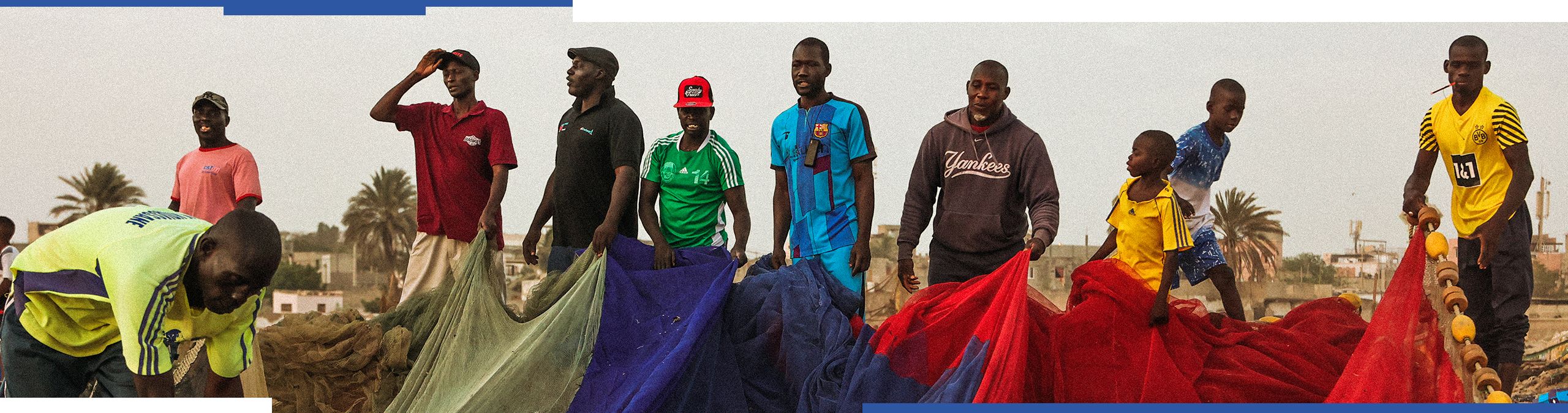 Un grupo de hombres sujetan redes de pesca. 